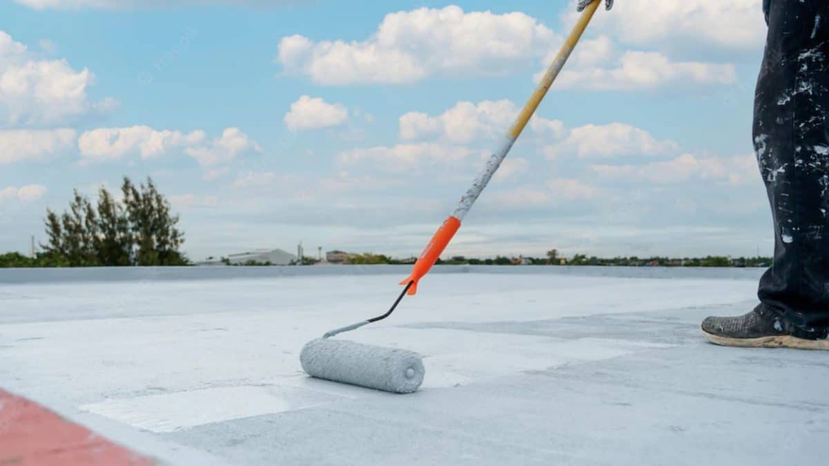 Worker applying protective roof coating on a Colorado building