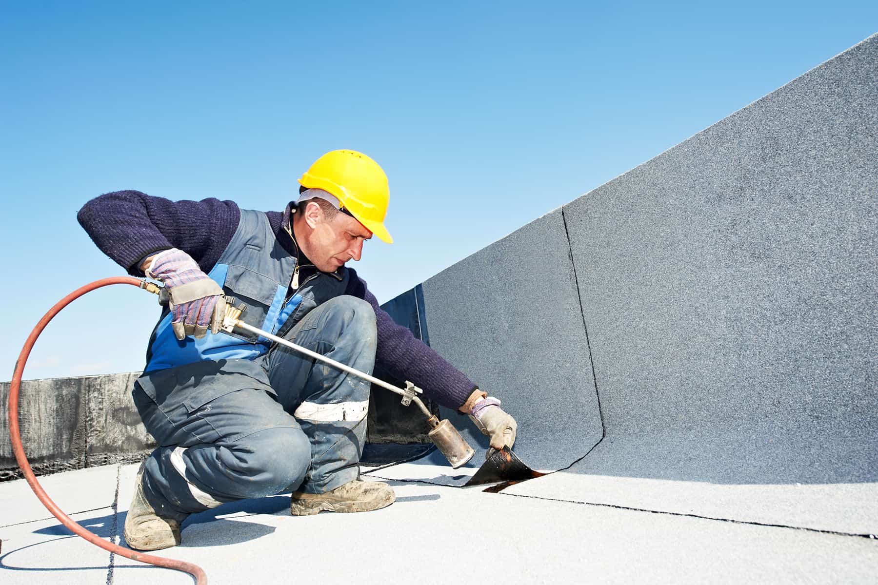 Technician repairing a flat roof after hail damage in Colorado