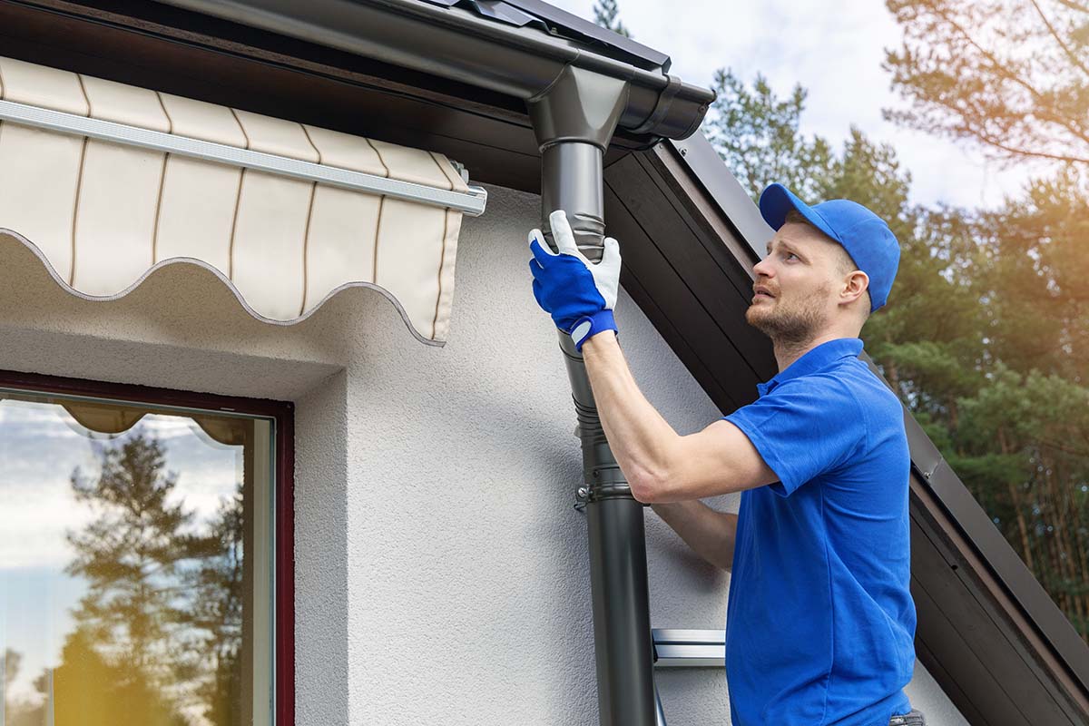 Technician repairing hail-dented gutters on a Colorado home